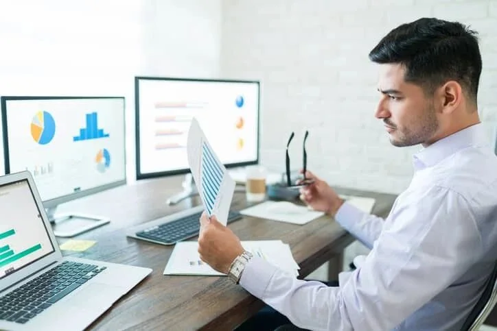 An analyst at a desk reviewing data charts